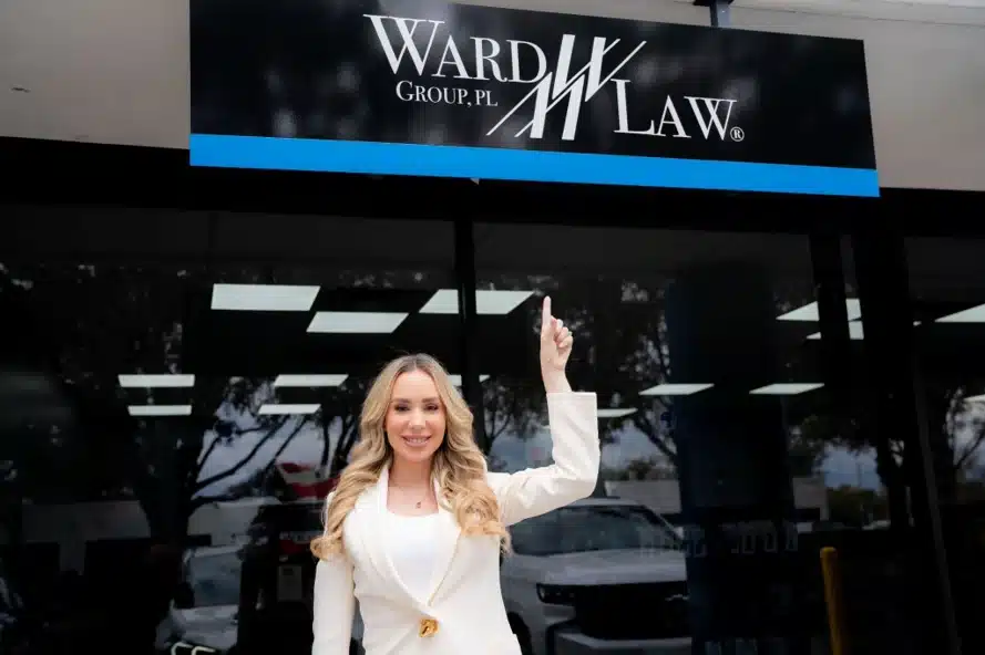 Ward Law attorney standing outside the Orlando office and pointing to the Ward Law sign.