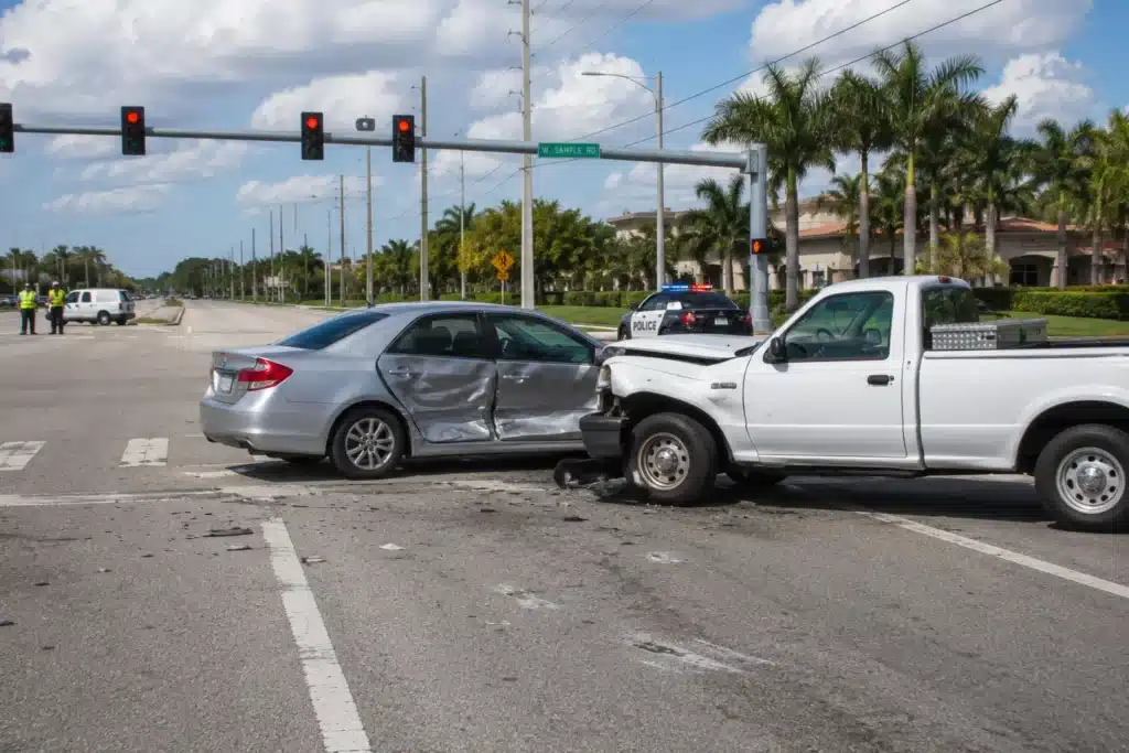 T-bone collision between a silver sedan and white pickup truck at an intersection, with police on scene